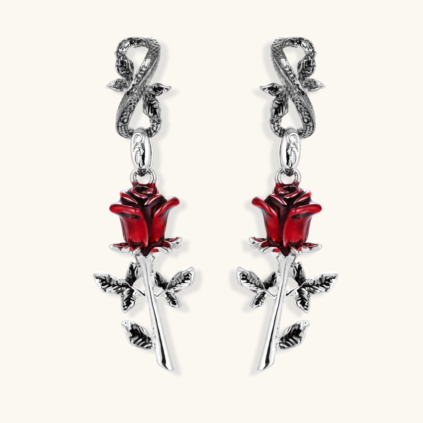 Gothic dangle earrings featuring silver serpent hooks with red enamel roses and metallic stems on white background.